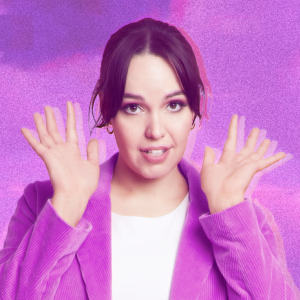 Bec has dark brown eyes and black, long hair which is tied back. She is smiling gently at the camera, wearing hoop earrings and a pink corduroy jacket over a white tshirt. Her hands are up beside her cheeks with her fingers blurred like they are moving. She is in front of a pink & purple backdrop.