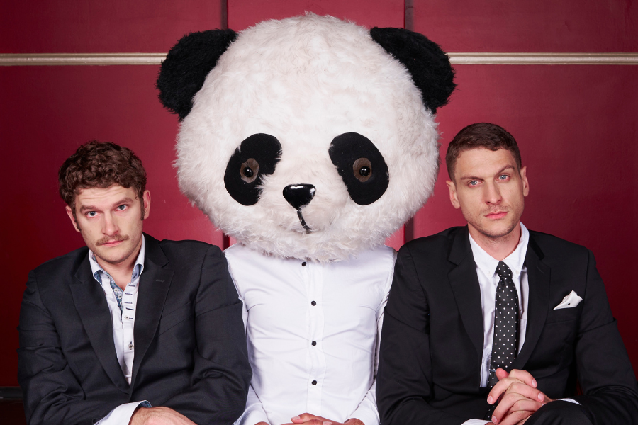 Image is of Carlo Ritchie (left) and Steen Raskopoulos (right). Both men are wearing suits and sitting next to a Panda Mascot. 