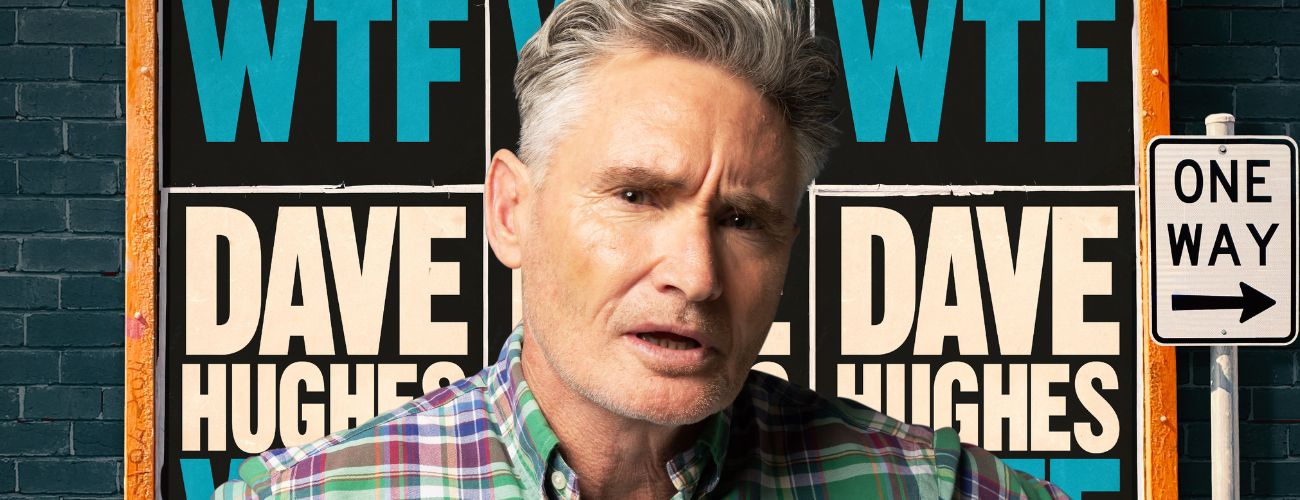 Image is of Dave Hughes standing in front of a poster wall 'WTF'