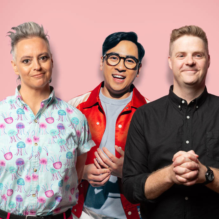 Composite image of (from left of shot to right) Geraldine Hickey, Michael Hing and Tom Ballard. Each comedian is pictured from the waist up. Michael is behind Geraldine and Tom. The background is light pink. Geraldine has short grey hair and brown eyes. She is wearing a white button up shirt with pink, purple and blue jellyfish. She has bright pink pants and a black belt on. She is smiling at the camera. Michael wears an orange jacket made of synthetic material with white trim over the shoulders. The jacket is unbuttoned down the front, showing an off-white t-shirt. He has glasses on with dark brown glass frames and his black hair is neatly parted to his right. He holds the ring on the ring finger of his right hand in all digits of his left hand at his midriff. He is smiling at the camera. Tom has short blonde hair and blue eyes. He is wearing a black buttoned up top and is standing in front of a light pink backdrop. He is smiling just outside of the camera lens and has his hands clasped together in front of his stomach.