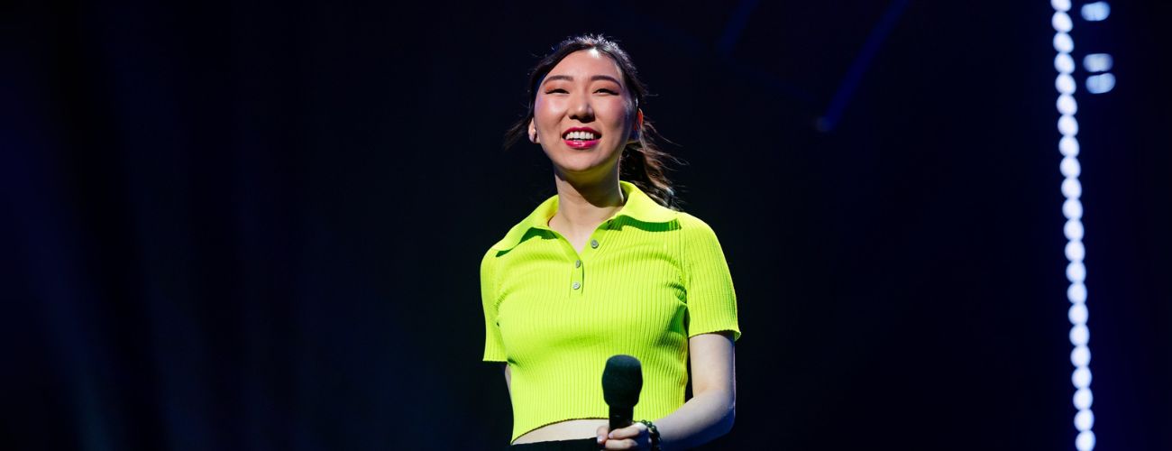 Jenny Tian on stage. She's smiling and holding a microphone.