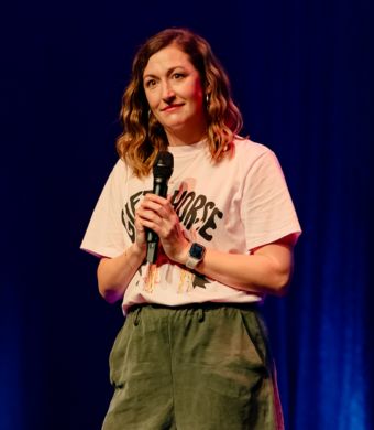 Celia Pacquola on stage holding a microphone